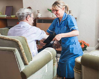 senior woman getting her blood pressure read by a caregiver