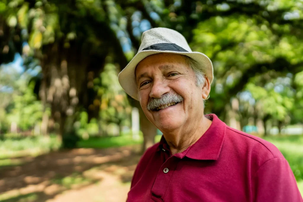 A senior Man outside smiling while thinking about senior living buy-in vs monthly rent​ communities like Burcham Hills.
